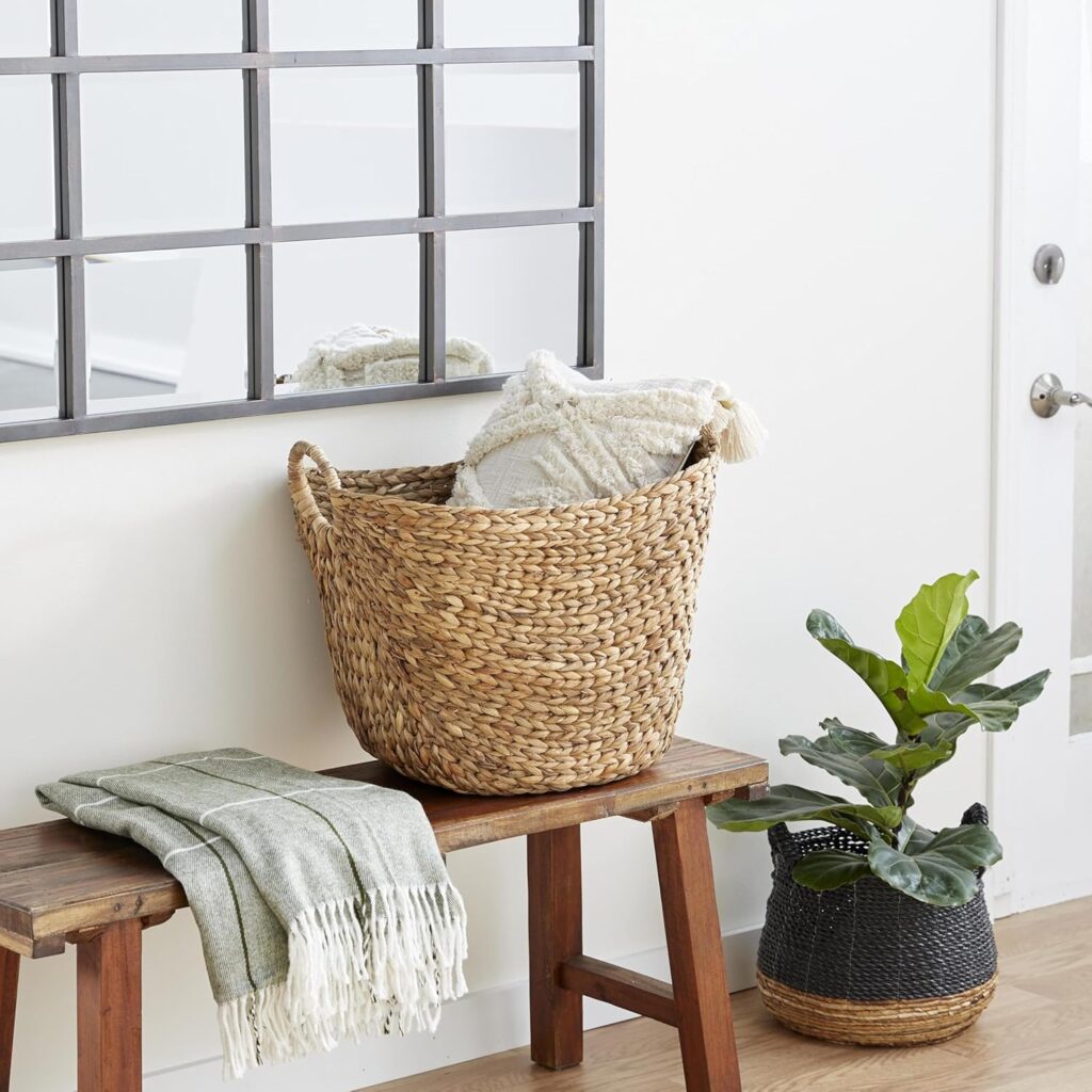 tall seagrass woven basket with handles beside a bed for cottage core storage