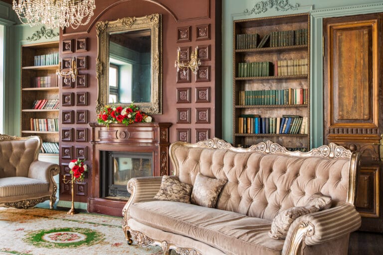Victorian Home Decor living room with tufted sofa, ornate fireplace, built in bookshelves, and antique details